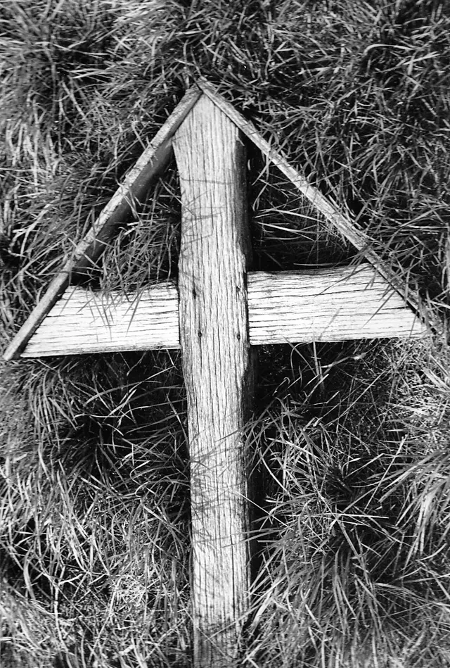 Old wooden cross lying in grass